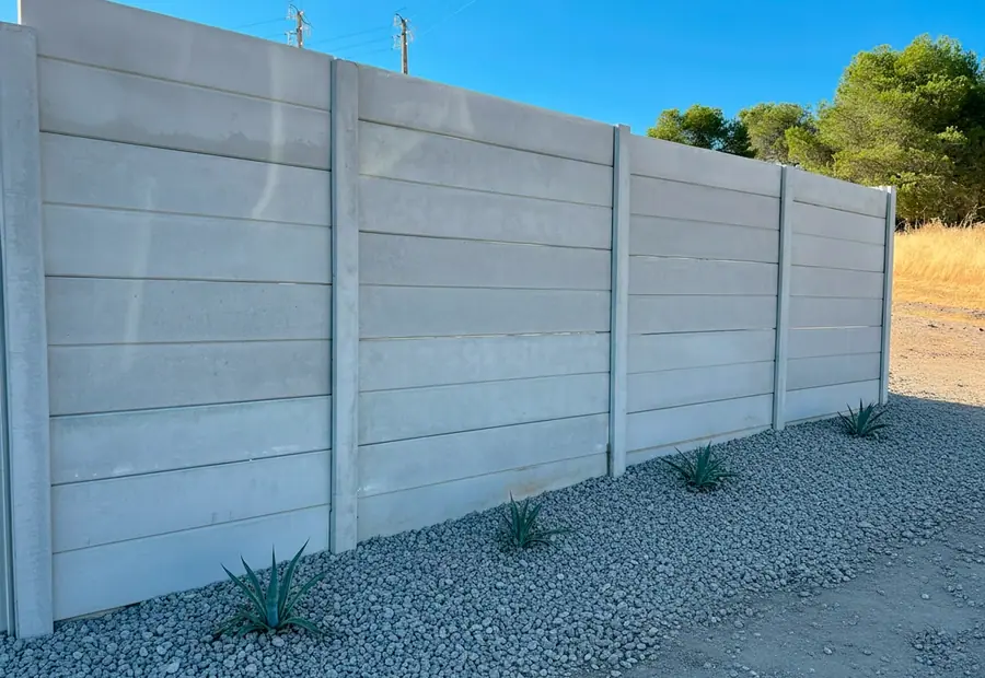 Precast concrete wall in white concrete with a smooth surface beside a gravel path